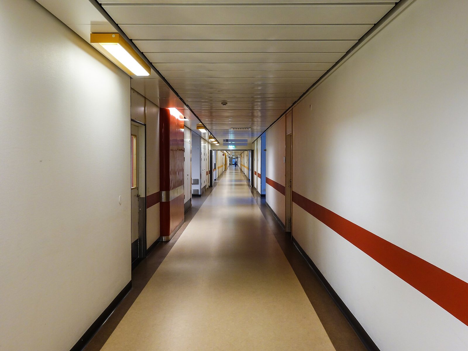 A long, empty hospital corridor with a red stripe along the wall